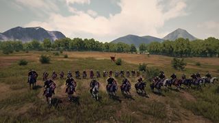 A line of horsemen charging across open ground beneath the mountains