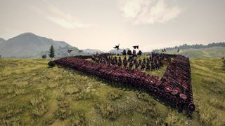 A shield wall of red shields curving across a hilltop