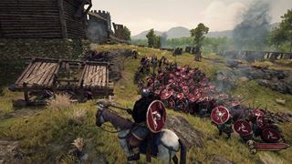 A siege assault — hundreds of men storming a hillfort, every shield carrying the triskelion of Mön
